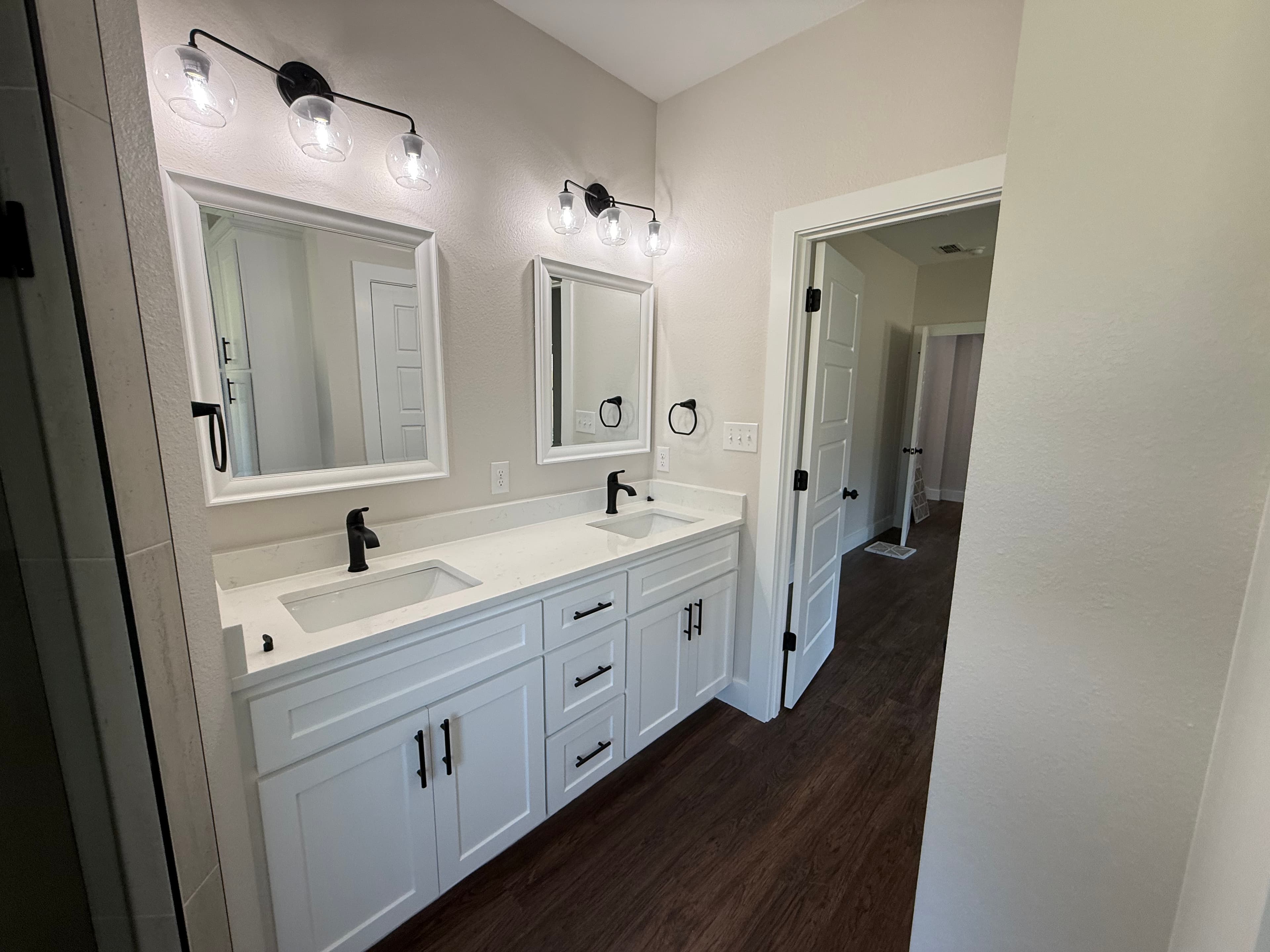 Double vanity bathroom with white cabinets and black fixtures.