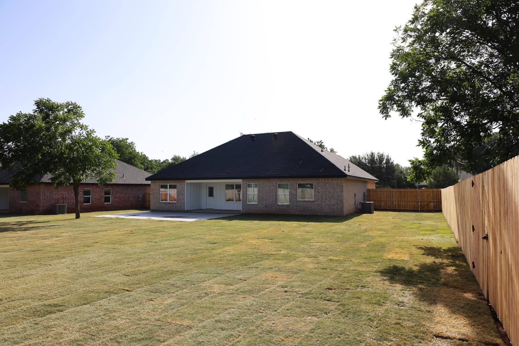 Rear elevation, covered patio, lawn, and fence at a Roadrunner custom home.