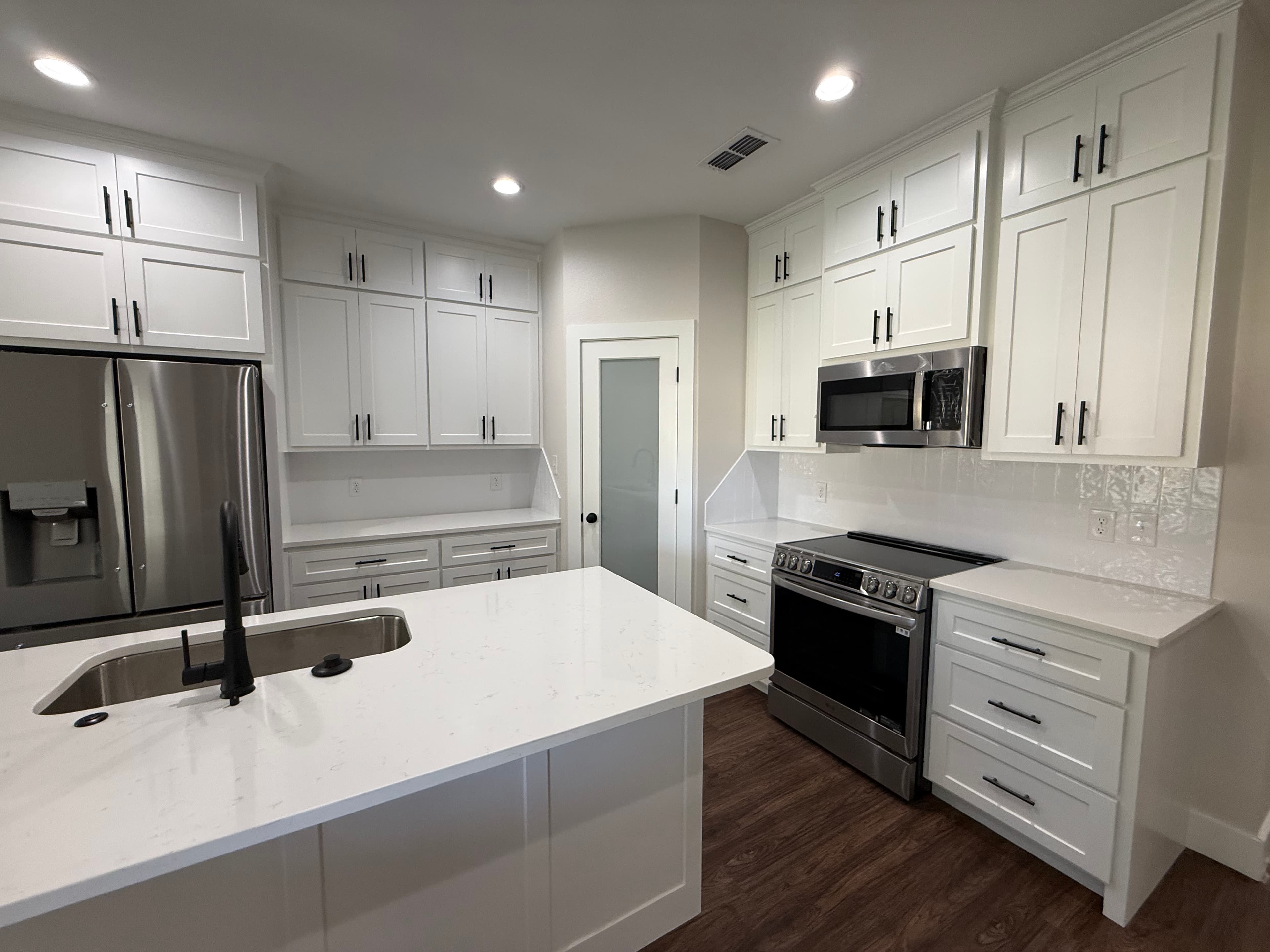 Bright white kitchen with a large island and black hardware.