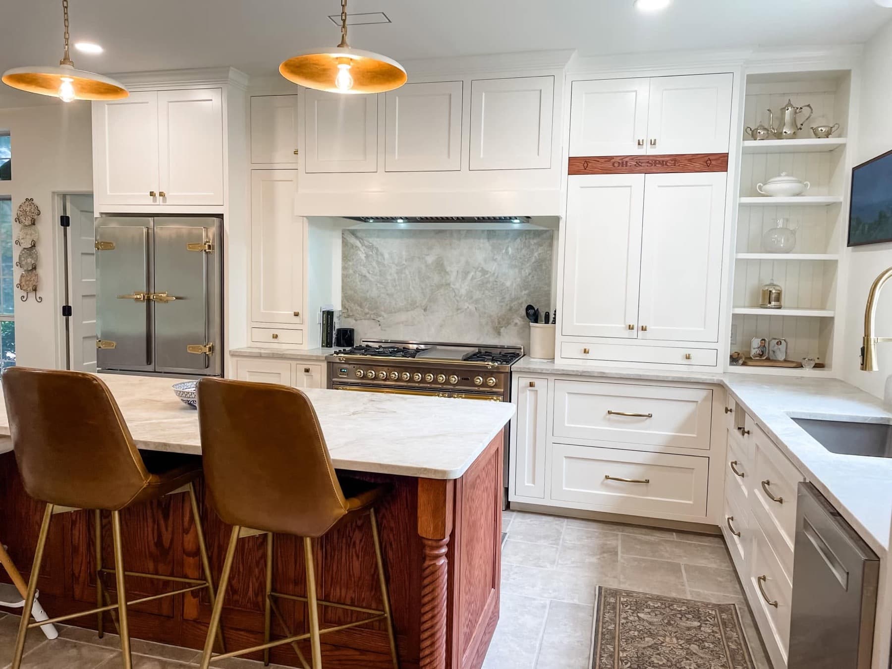 White custom kitchen with a warm wood island, brass fixtures, and tailored cabinetry.